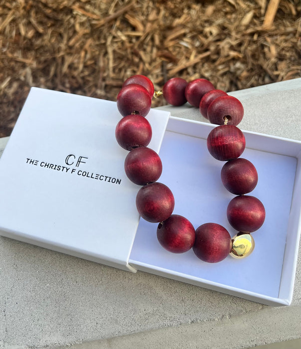 Red beaded necklace with a gold clasp on a white box labeled 'The Christy F. Collection'.