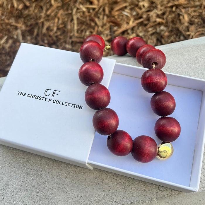 Red beaded necklace with a gold clasp on a white box labeled 'The Christy F. Collection'.