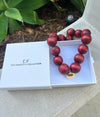 Necklace with red beads and gold clasp in a white box labeled 'The Christy F Collection'.