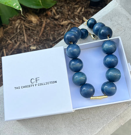 Blue beaded necklace in a box with 'The Christy F Collection' branding.