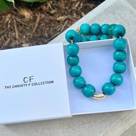 Turquoise beaded necklace with gold accents in a box labeled 'The Christy F Collection'.