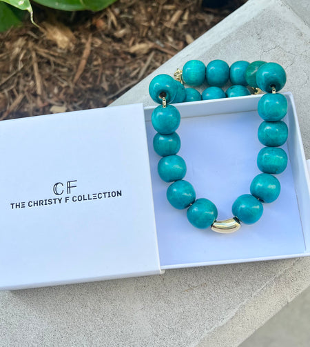 Turquoise beaded necklace with gold accents in a box labeled 'The Christy F Collection'.