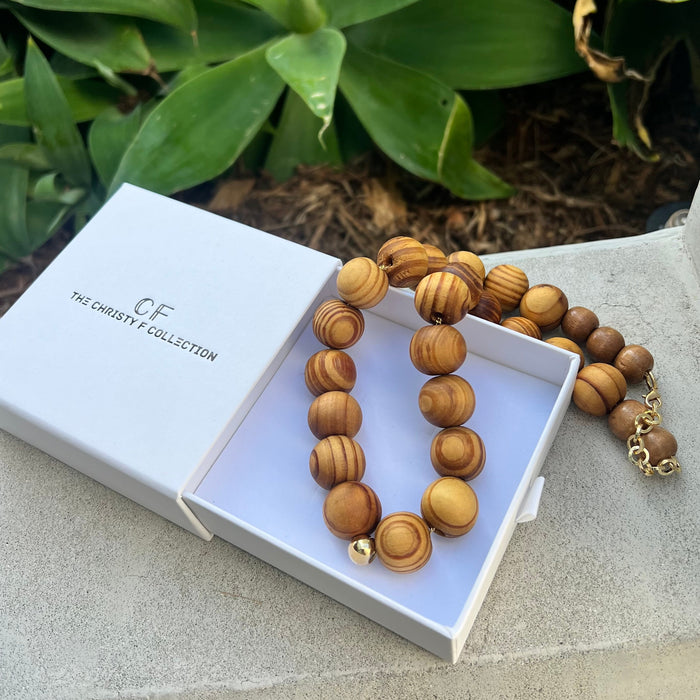 Wooden beaded necklace in a white box with 'The Christie Collection' branding, against a natural background.