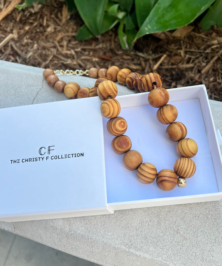 Wooden beaded necklace on a branded box with 'The Christy F Collection' branding.