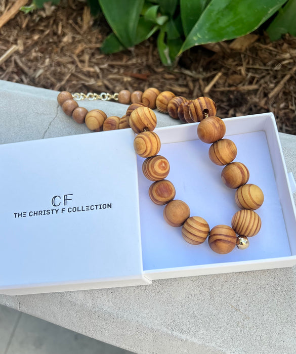 Wooden beaded necklace on a branded box with 'The Christy F Collection' branding.