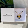 Floral necklace in a 'The Christy F Collection' box with a plant in the background