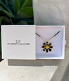 Floral necklace in a 'The Christy F Collection' box with a plant in the background