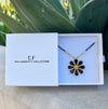 Floral necklace in a 'The Christy F Collection' box with plants in the background