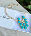 Necklace with turquoise pendant and beaded chain on a white box with 'CF' branding.