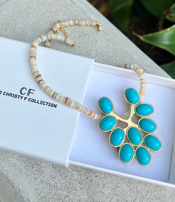 Necklace with turquoise pendant and beaded chain on a white box with 'CF' branding.
