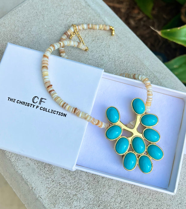 Turquoise pendant necklace with gold accents in a white box, branded 'The Christy F Collection'.