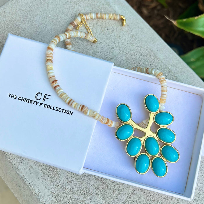 Turquoise pendant necklace with gold accents in a white box, branded 'The Christy F Collection'.