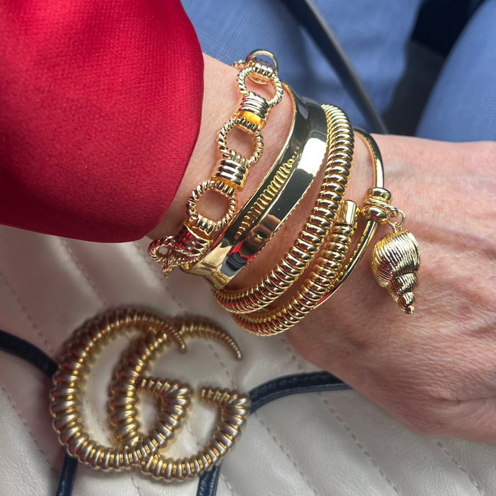 Close-up of a hand wearing gold bracelets and bangles.