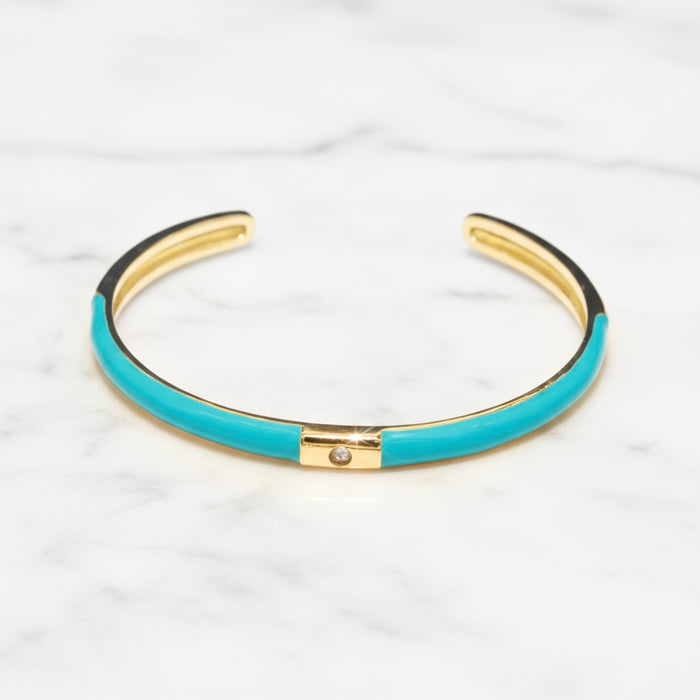 Turquoise bangle with gold accents on a white marble background