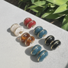 Set of colorful earrings on a textured surface with greenery in the background