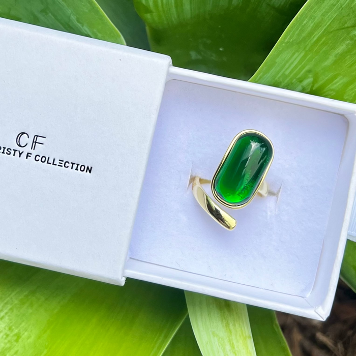 Green ring in a white box with 'C F Misty F Collection' branding, surrounded by green leaves.