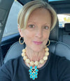 Woman sitting in a car wearing a necklace with a blue pendant