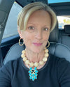 Woman sitting in a car wearing a necklace with a blue pendant