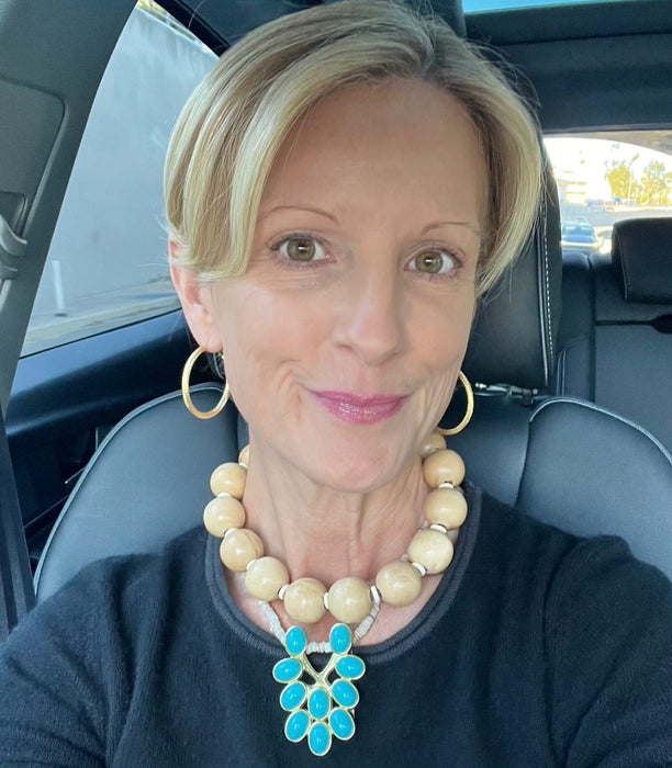 Woman sitting in a car wearing a necklace with a blue pendant