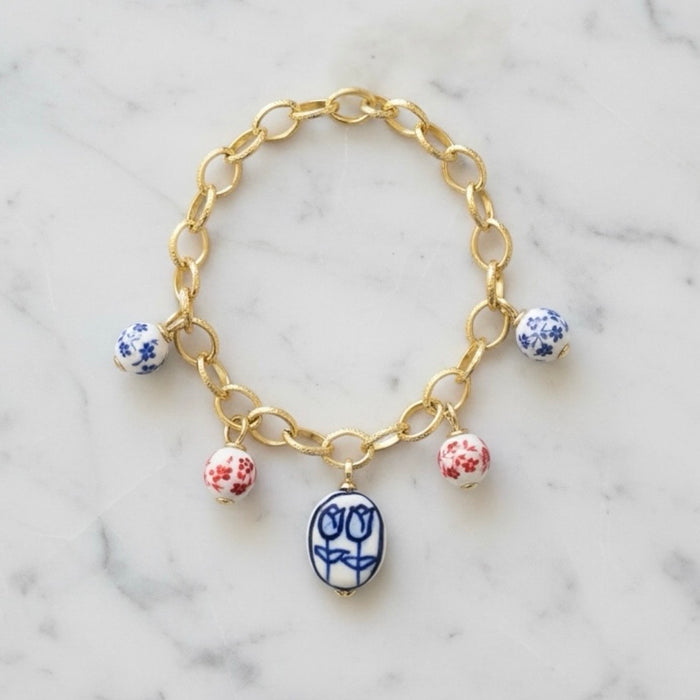 Gold chain bracelet with ceramic beads on a marble surface