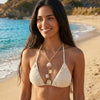Woman in a beige bikini standing on a beach with ocean in the background