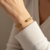 Gold bracelets on a wrist with a neutral background