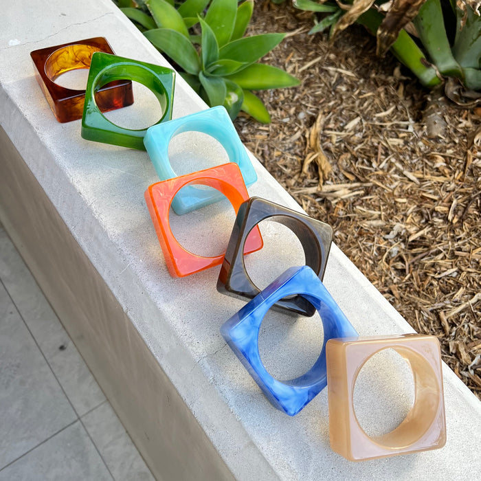 Colorful geometric bangles on a stone ledge with plants in the background