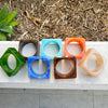 Set of colorful geometric bangles on a concrete surface with a natural background.