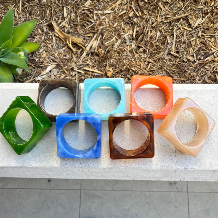 Set of colorful geometric bangles on a concrete surface with a natural background.