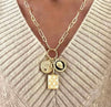 Gold necklace with charms on a beige sweater