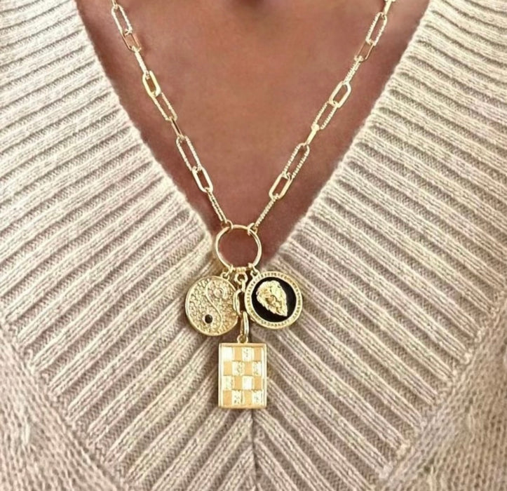 Gold necklace with charms on a beige sweater
