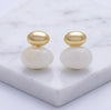Pair of gold and white earrings on a marble surface