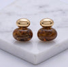 Pair of gold and brown earrings on a marble surface
