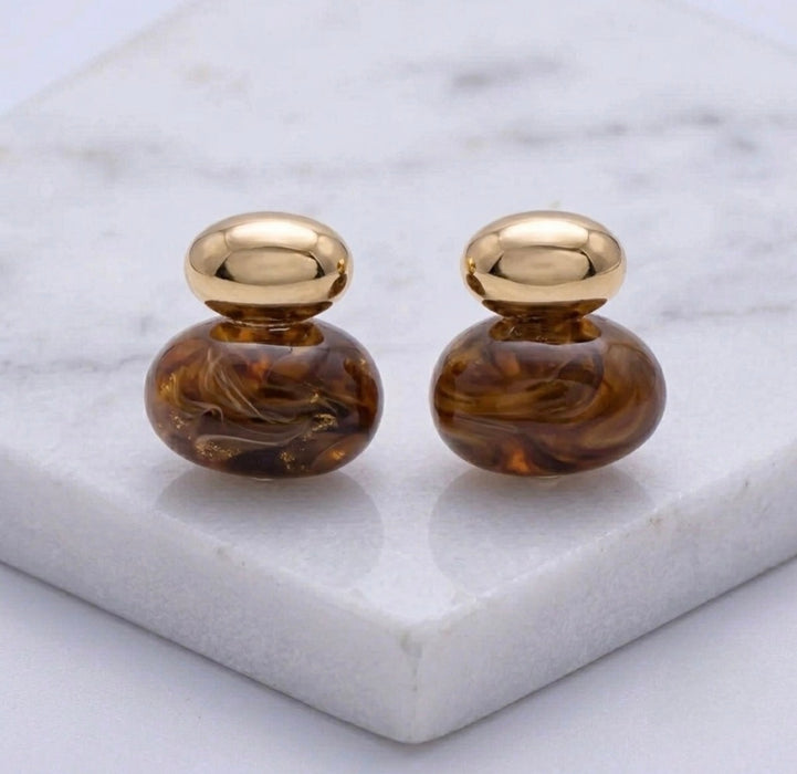 Pair of gold and brown earrings on a marble surface