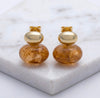 Gold and amber glass earrings on a marble surface