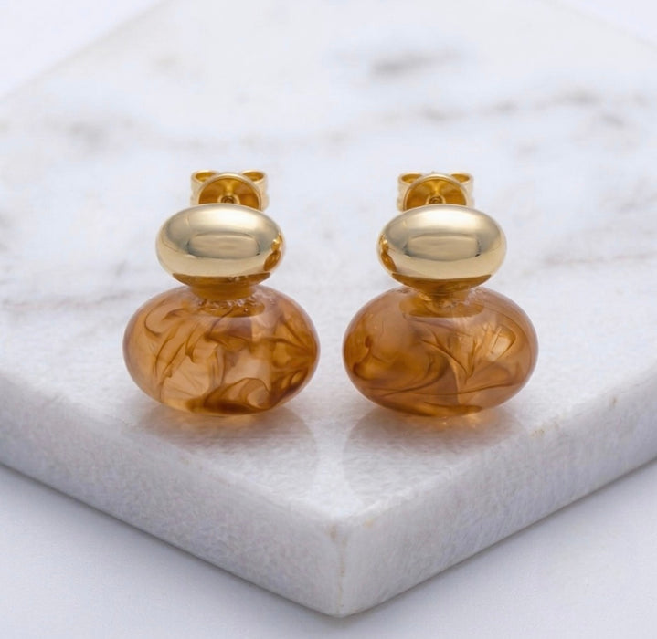 Gold and amber glass earrings on a marble surface