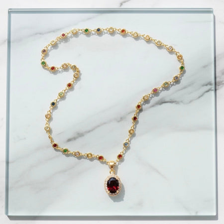 Gold necklace with gemstones on a marble surface