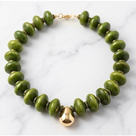 Green beaded bracelet with a gold clasp on a marble surface