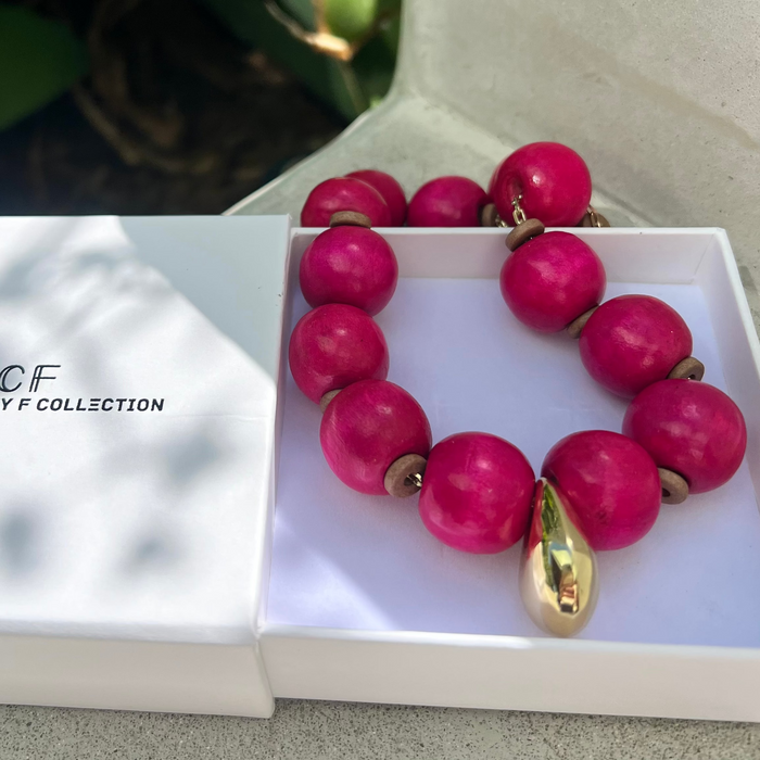 Pink beaded necklace with gold accents on a white box, branded 'CF Hristy F Collection'.