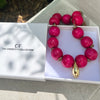 Pink beaded bracelet with gold accents on a white box, branded 'The Christy F Collection'.