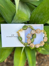 Two beaded bracelets on a white card with 'CF' branding, set against a green leafy background.