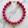 Necklace with pink beads and a gold clasp on a marble background