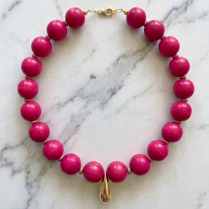 Necklace with pink beads and a gold clasp on a marble background