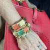 Hand wearing multiple colorful bracelets on a red textured surface