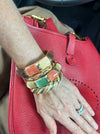 Hand wearing multiple colorful bracelets on a red textured surface