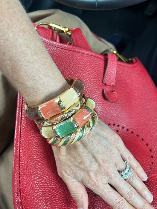 Hand wearing multiple colorful bracelets on a red textured surface