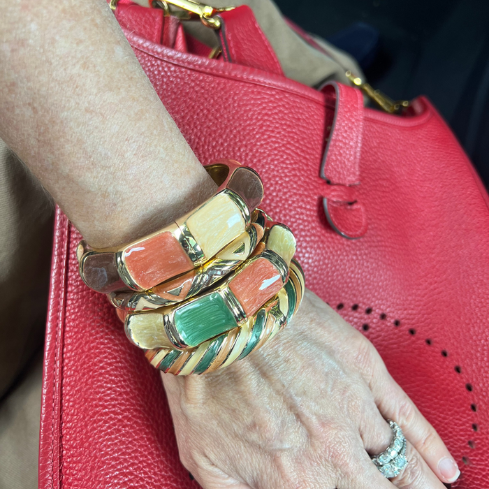 Hand wearing multiple colorful bracelets on a red textured surface