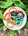 Colorful resin bracelets on a white plate with green leaves in the background