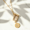 Gold necklace with a pendant featuring the letter 'C' on a marble background