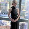 Woman in a black dress standing in front of a cityscape view